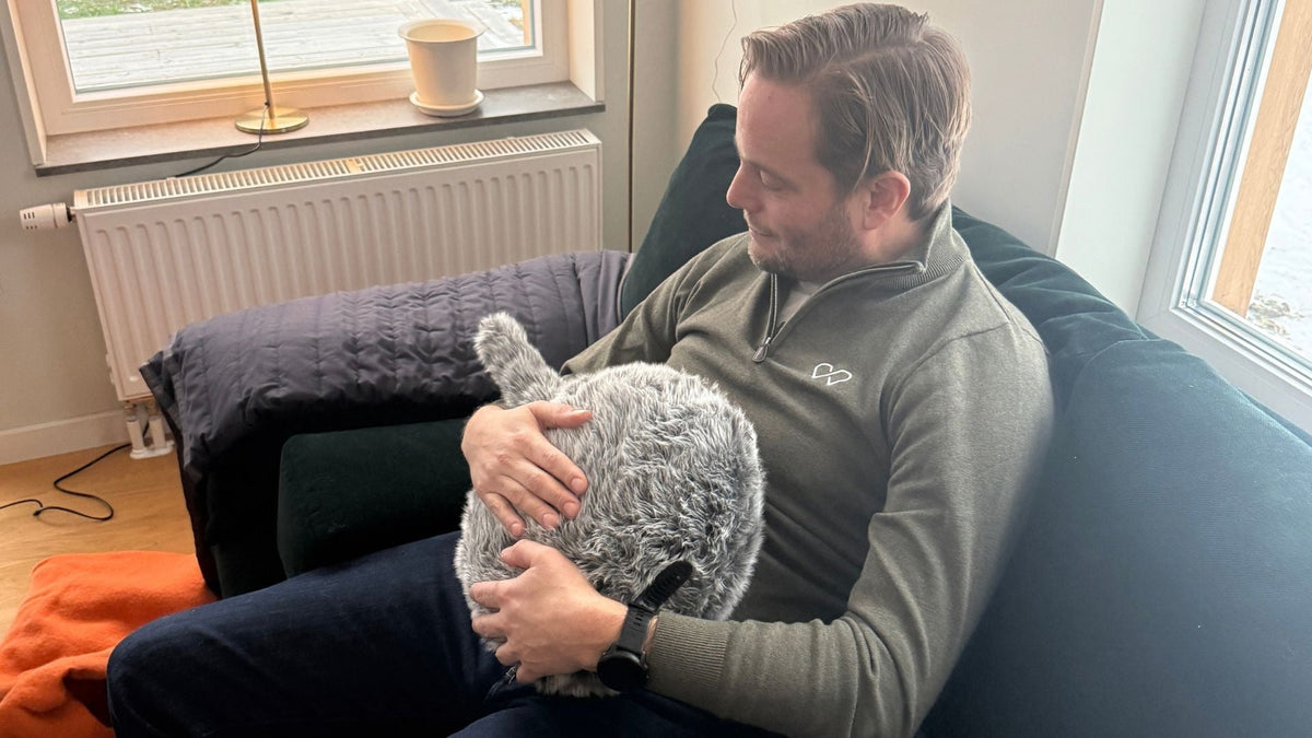 Fredrik sitter med Qoobo i soffan på SilivaBo